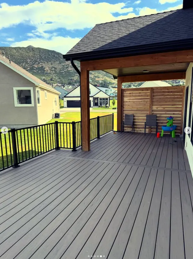 Covered custom deck with black railing by Frame Platinum LLC