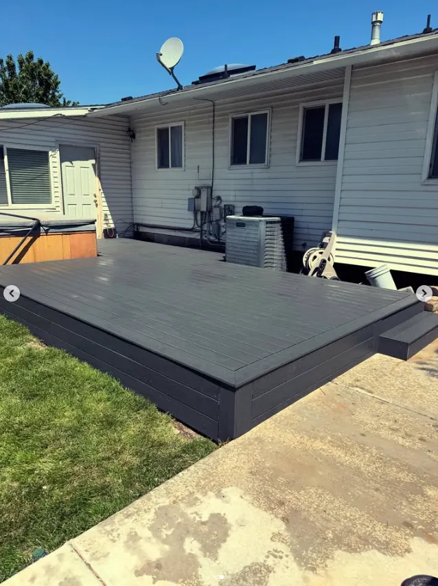 Dark composite deck next to the lawn by Frame Platinum LLC