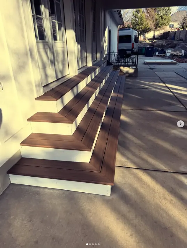 Wide front entry steps with brown treads and white risers by Frame Platinum LLC